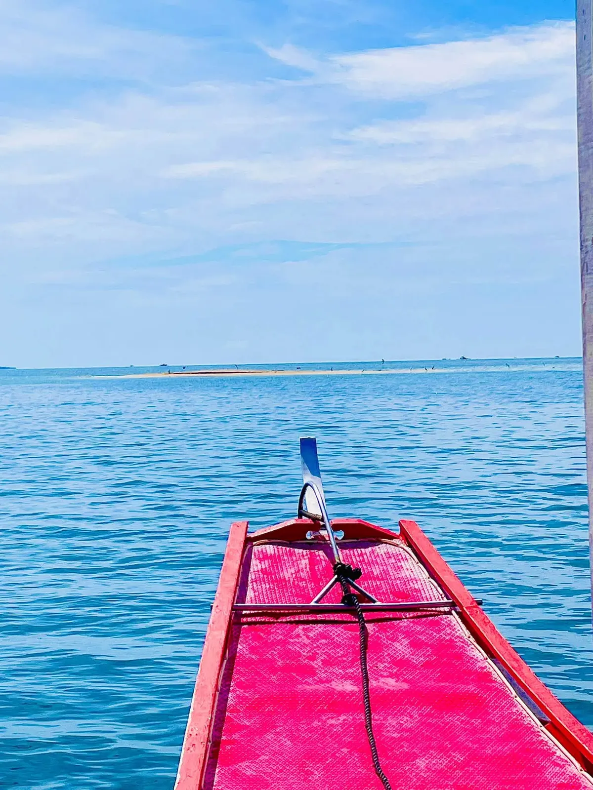The pink bow of a bangka heading out over calm blue water