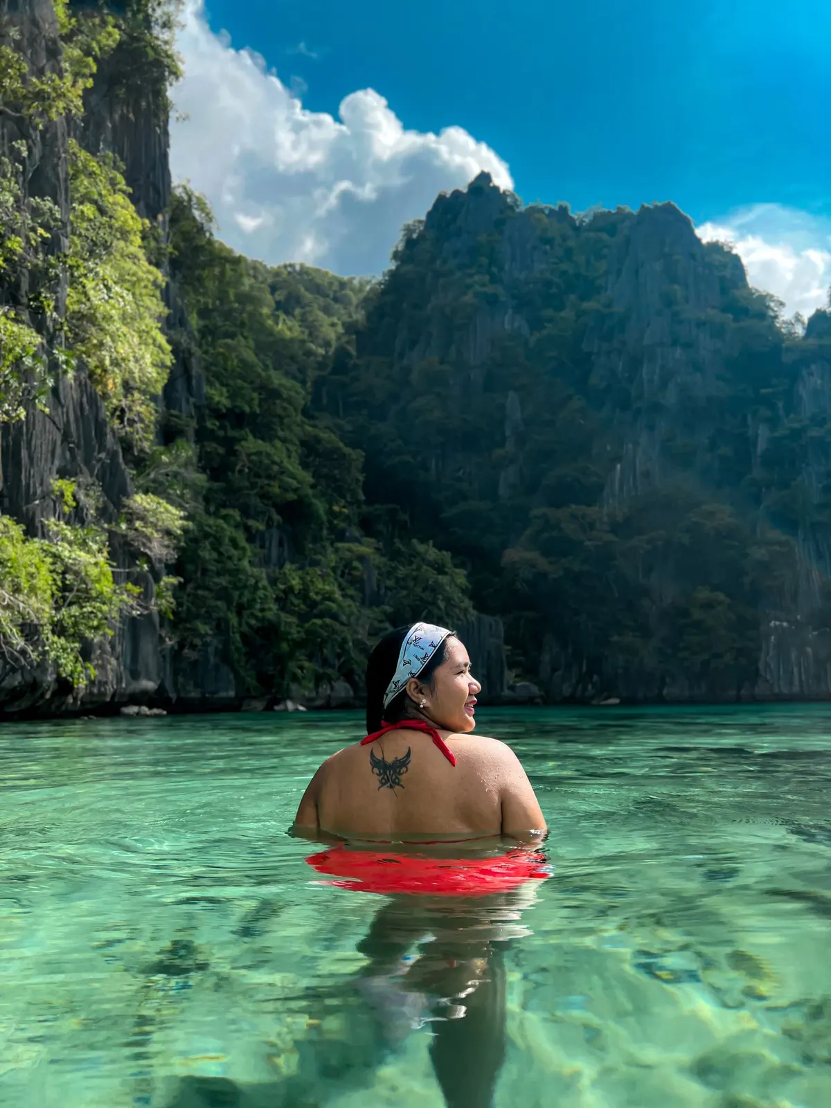 A swimmer in a clear green lagoon below cliffs in Coron (illustrative photo)