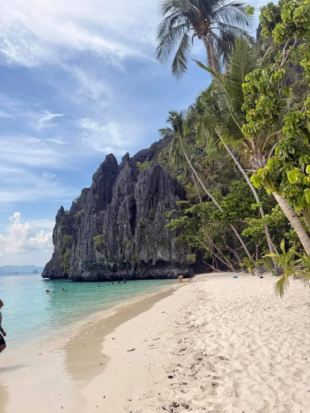 A white-sand cove under a jagged limestone headland