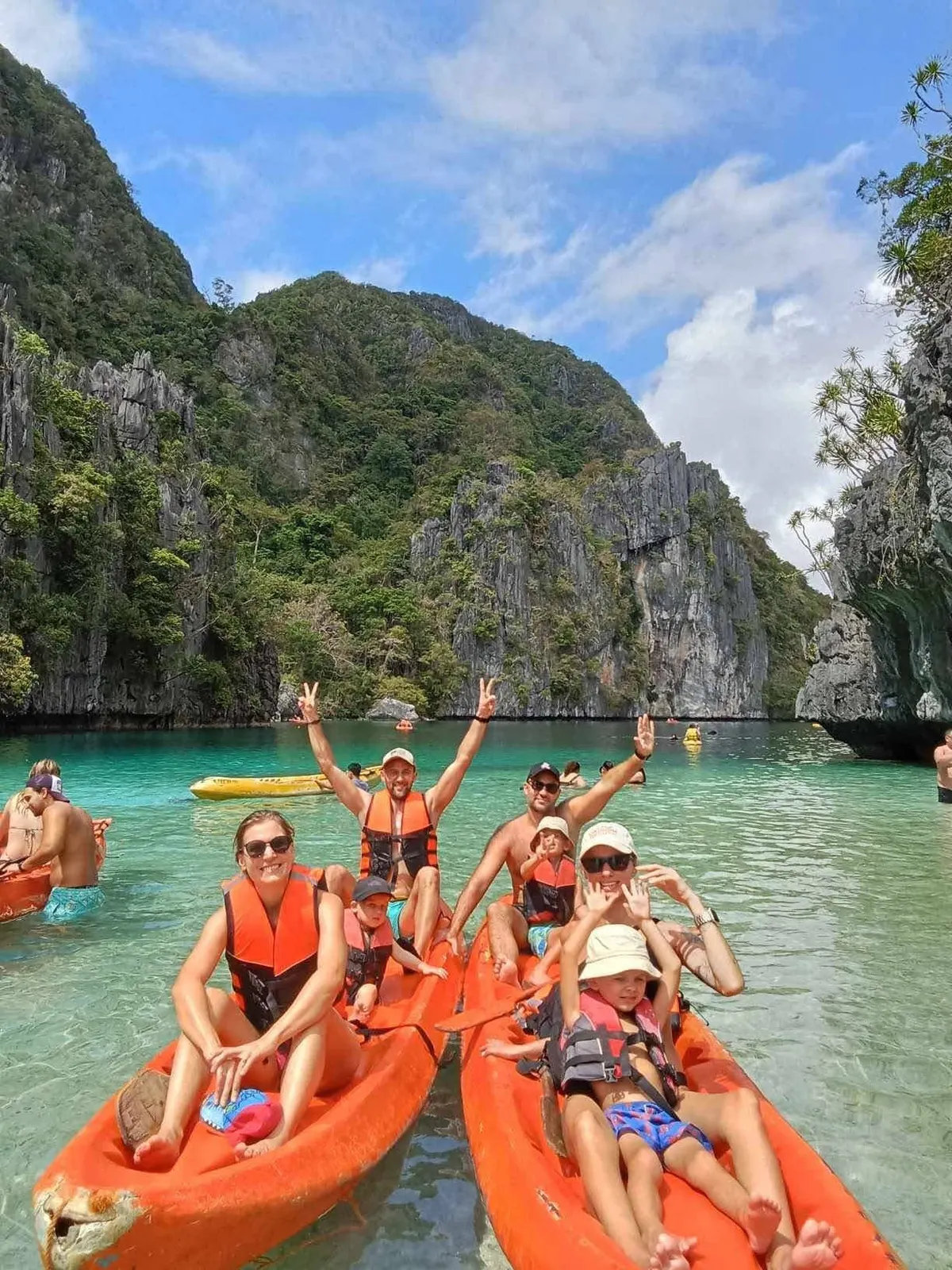East Jeanna guests waving from orange kayaks in an El Nido lagoon