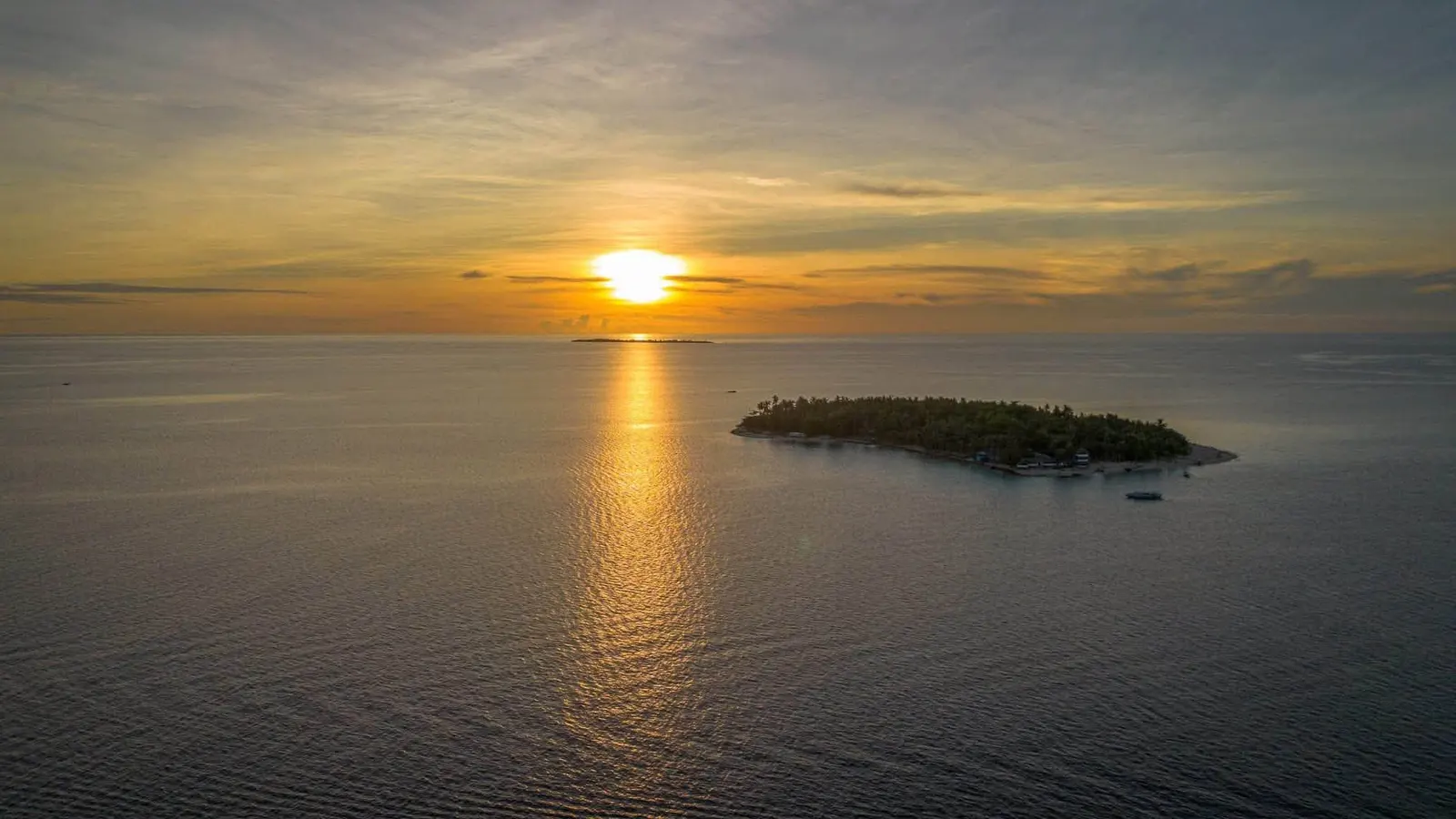 Sunset over the sea with a small island on the horizon